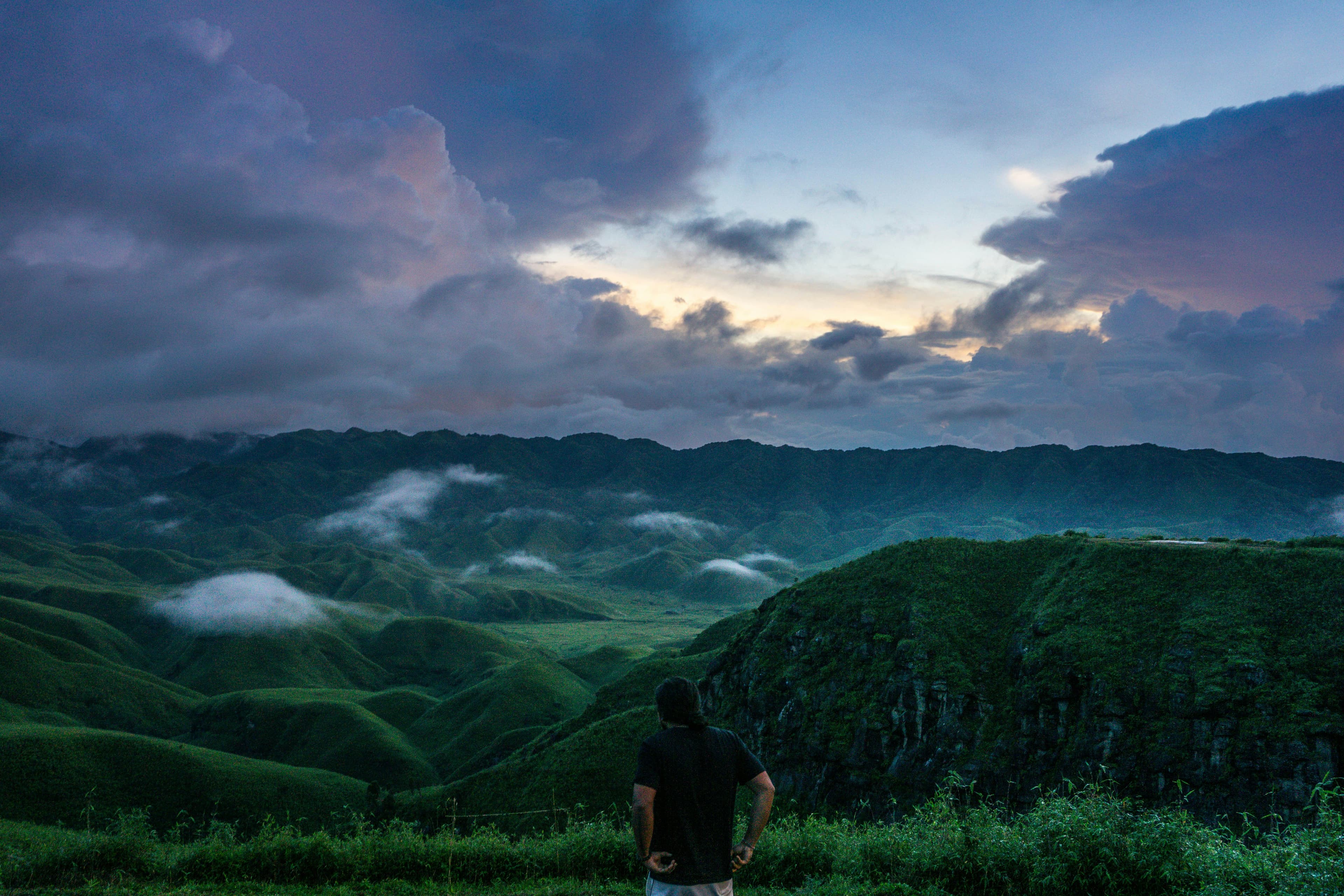 A trekker standing before Dzukou Valley at twilight